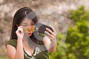 Young happy and beautiful Asian Chinese woman taking selfie photo with mobile phone posing playful and carefree in hipster