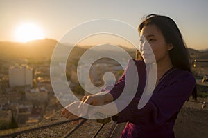 Young happy and beautiful Asian Japanese woman outdoors at viewpoint balcony enjoying sunset view of Spain town during Europe