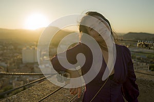 Young happy and beautiful Asian Japanese woman outdoors at viewpoint balcony enjoying sunset view of Spain town during Europe