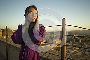 Young happy and beautiful Asian Japanese woman outdoors at viewpoint balcony enjoying sunset view of Spain town during Europe