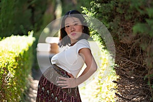 Young happy and beautiful Asian Japanese woman posing outdoors happy and cheerful at city park pregnant showing her belly proud