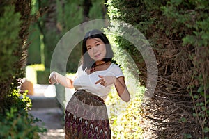 Young happy and beautiful Asian Japanese woman posing outdoors happy and cheerful at city park pregnant showing her belly proud