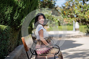 Young happy and beautiful Asian Japanese woman pregnant showing her belly proud and cheerful smiling at city park bench happy in