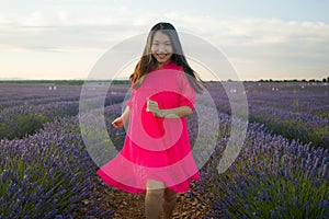 Young happy and beautiful Asian Japanese woman in Summer dress enjoying nature free and playful outdoors at purple lavender