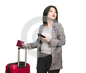 Young happy and beautiful Asian Korean woman carrying suitcase holding passport and mobile phone ready for holidays trip smiling