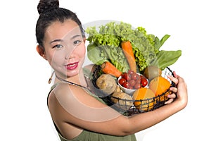 Young happy and beautiful Asian Korean woman holding basket full of fresh vegetables and fruits smiling cheerful  in healthy