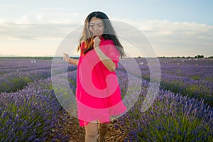 Young happy and beautiful Asian Korean woman in Summer dress enjoying nature running free and playful outdoors at purple lavender