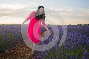 Young happy and beautiful Asian Korean woman in Summer dress enjoying nature running free and playful outdoors at purple lavender