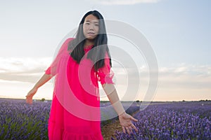 Young happy and beautiful Asian Korean woman in Summer dress enjoying nature running free and playful outdoors at purple lavender