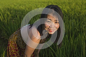Young happy and beautiful Asian woman enjoying nature at rice field. sweet Chinese girl exploring countryside during holiday