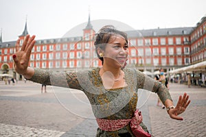 Young happy and beautiful Asian woman wearing traditional Balinese kebaya dress - Indonesian girl doing Bali dance on street