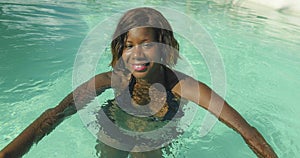 Happy and beautiful black African American woman in bikini having fun at tropical beach resort swimming pool relaxed and playful