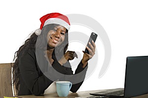 Young happy and beautiful black afro American business woman in Santa Christmas hat working at office computer desk smiling succes