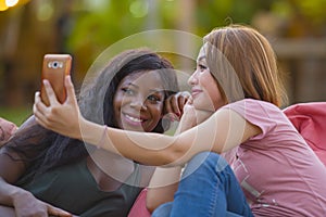 Young happy and beautiful black afro American woman enjoying holidays at tropical resort with Asian girlfriend taking selfie