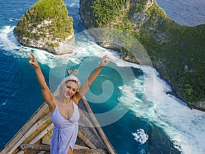 Young happy and beautiful blond woman relaxed at tropical beach cliff viewpoint enjoying Summer holidays getaway carefree at