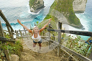 Young happy and beautiful blond woman smiling cheerful at tropical beach cliff landscape enjoying Summer holidays getaway carefree