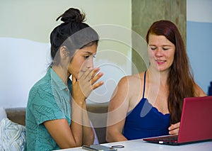 Young happy and beautiful caucasian and latin women working at office cafe with laptop computer discussing as digital business