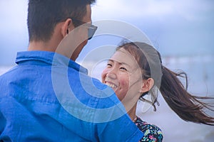 Young happy and beautiful Chinese Asian couple with woman hug her boyfriend romantic and cuddle on the beach