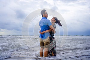 Young happy and beautiful Chinese Asian couple with woman hug her boyfriend romantic and cuddle on the beach