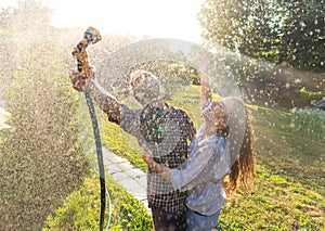 Young happy beautiful couple hosing in the garden, summer happiness and love concept