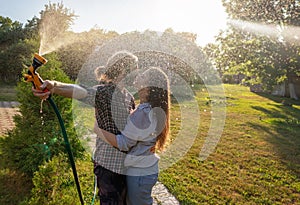 Young happy beautiful couple hosing in the garden, summer happiness and love concept