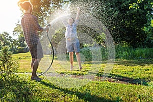 Young happy beautiful couple hosing in the garden, summer happiness and love concept, poured water from a garden hose of a spray