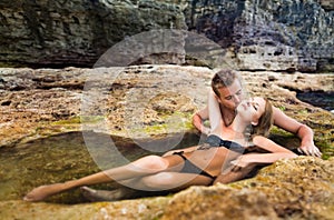 Young happy beautiful couple woman and man enjoying time in natural rock pool with water with rocks wall at background
