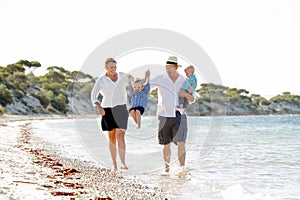 Young happy beautiful family walking together on the beach enjoying summer holidays