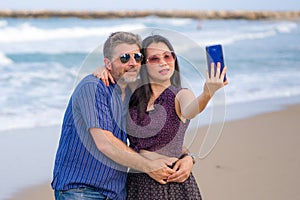 Young happy and beautiful mixed ethnicity couple in love with Asian woman and Caucasian man taking sweet selfie with mobile phone