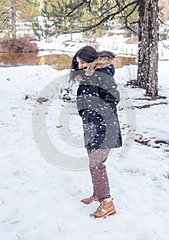 Young happy and beautiful teenage girl dressed in winter clothing standing at snow and smiling