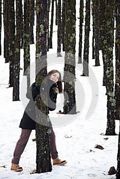 Young happy and beautiful teenage girl dressed in winter clothing standing at snow and smiling