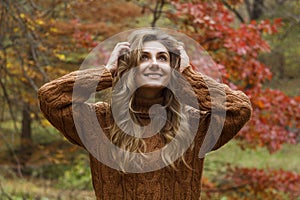 Young happy beautiful woman with curly hair having good time in autumn park