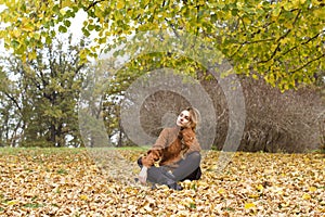 Young happy beautiful woman with curly hair having good time in autumn park