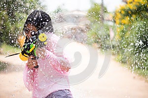 Young happy beauty Asian girl with water gun wearing summer shirt in Songkran festival - water festival in Thailand