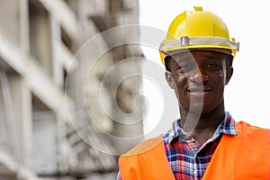 Young happy black African man construction worker smiling at bui