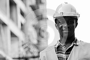Young happy black African man construction worker smiling at building site