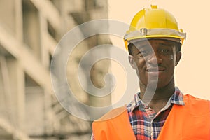 Young happy black African man construction worker smiling at building site