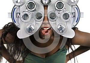 Young and happy black afro American woman at hospital looking through optometric hospital device checking eyes having sight exam