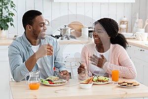 Young happy black couple having healthy breakfast together in kitchen at home