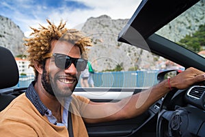 Happy black man driving a convertible car.