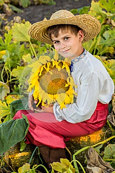 Young happy boy hold sunflower in a garden