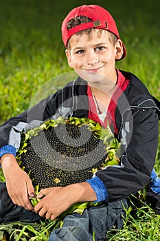 Young happy boy hold sunflower in a garden