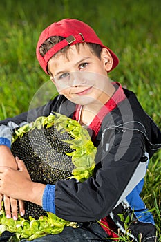 Young happy boy hold sunflower in a garden