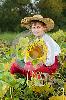 Young happy boy hold sunflower in a garden