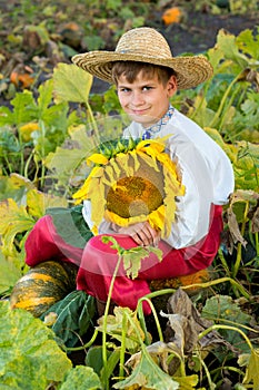 Young happy boy hold sunflower in a garden