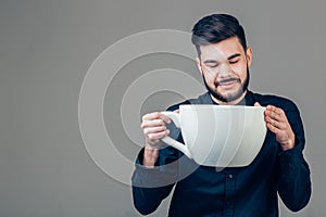 Business man holding a funny huge and oversized cup of black coffee in caffeine