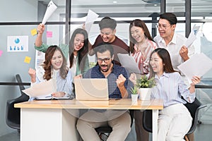 Young happy business men and women in informal clothes celebrate success looking at laptop screen in office. Diversity successful