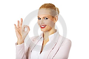 Young happy business woman shows OK sign