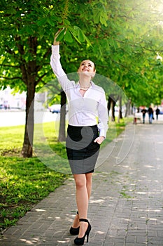 Young and happy business woman walking in city green park