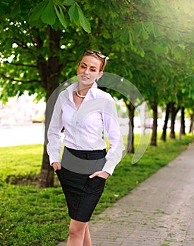 Young and happy business woman walking in city green park